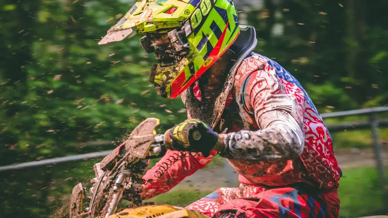 An off-road rider in a bright helmet on a forest trail