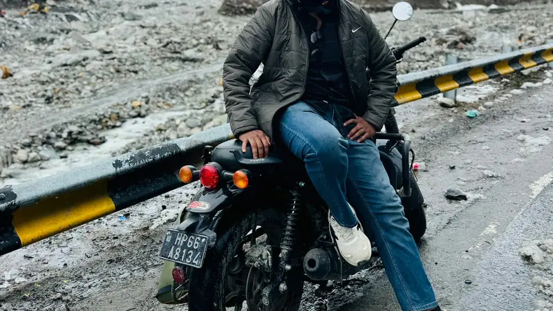 A rider on a motorcycle beside a snowy mountain road
