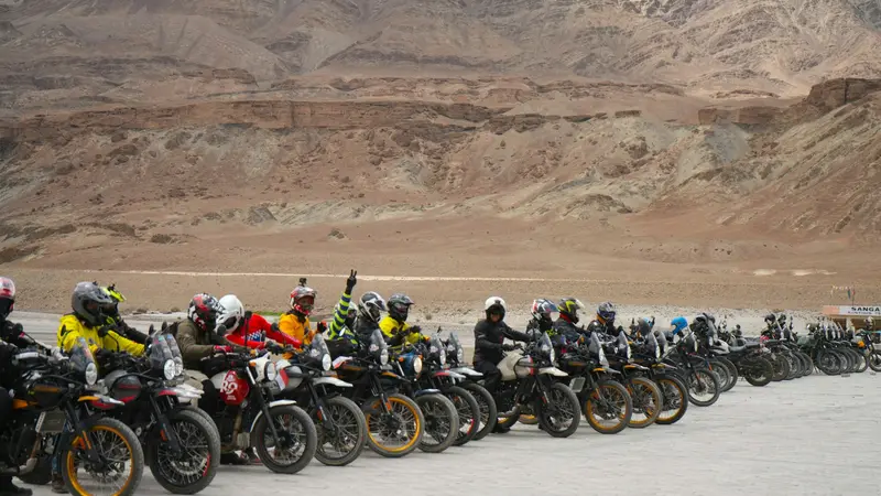 Riders lined up with their motorcycles in a desert valley